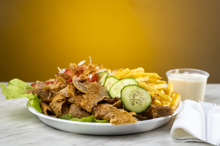 meat with kebab, French fries and salad on a plastic plateの写真素材