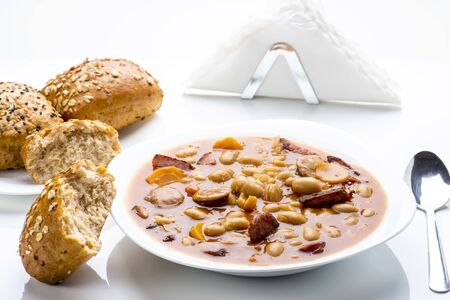 Baked beans with sausage and vegetables on a white table