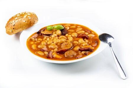 Baked beans with sausage and vegetables on a white tableの写真素材