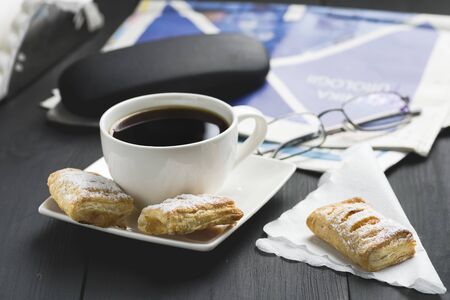a cup of coffee and something sweet to the morning newspaper - nice start to the dayの写真素材