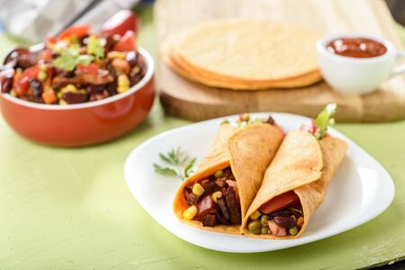 Tacos - delicious tortillas with meat and vegetables served with a spicy sauceの写真素材