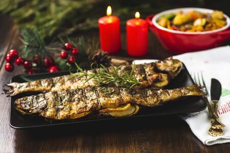 Grilled trout stuffed with vegetables on black plateの写真素材