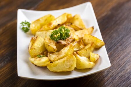 baked potato quarters on a white plate on a wooden tableの写真素材