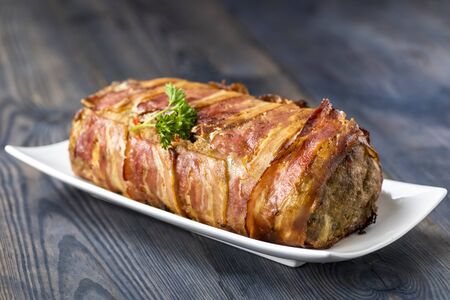 baked roulade of minced meat stuffed with spinach and peppers surrounded by baconの写真素材