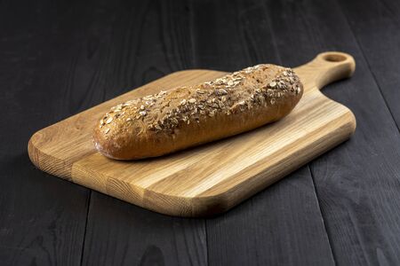 bread on a chopping board on a wooden kitchen table - rustic style photoの写真素材