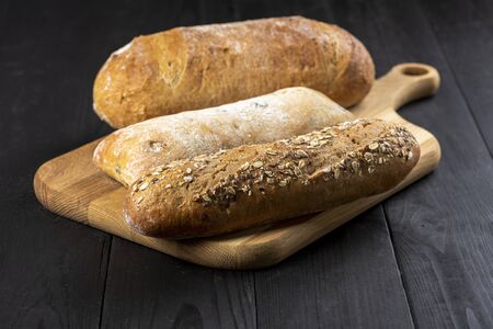 bread on a chopping board on a wooden kitchen table - rustic style photoの写真素材