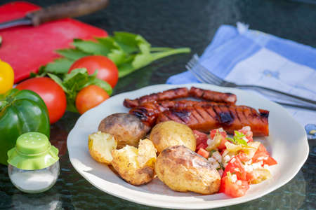 grilled sausage with baked potatoes and tomato saladの写真素材