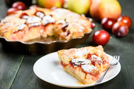 homemade apple and plum cake on wooden tableの写真素材