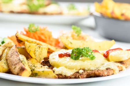 Hawaiian cutlet with baked potatoes and a bouquet of saladsの写真素材