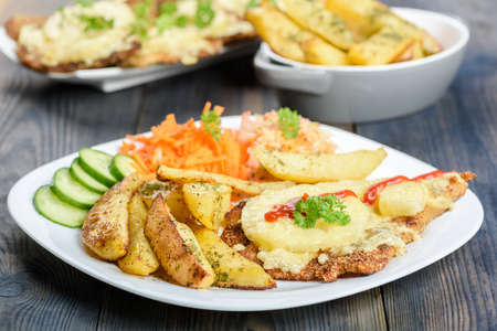 Hawaiian cutlet with baked potatoes and a bouquet of saladsの写真素材