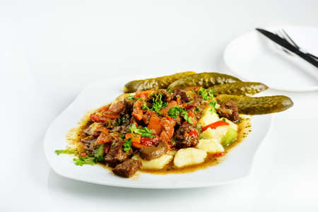 potato dumplings with goulash and cucumber