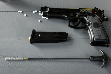 Cleaning the gun is an important part of ASG games. A working weapon is an element of a successful game. Disassembled pistol on a wooden table.の写真素材