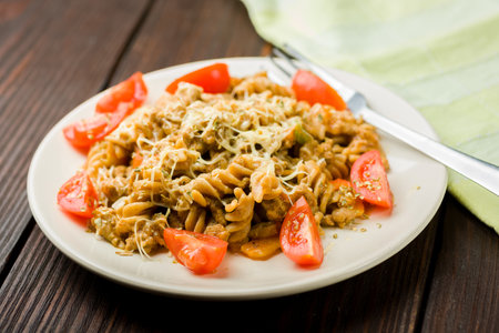 pasta with minced meat, tomato sauce and pieces of tomatoes on a wooden tableの写真素材