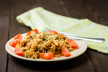 pasta with minced meat, tomato sauce and pieces of tomatoes on a wooden tableの写真素材
