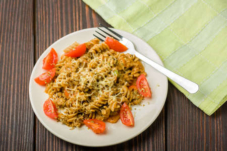 pasta with minced meat, tomato sauce and pieces of tomatoes on a wooden tableの写真素材