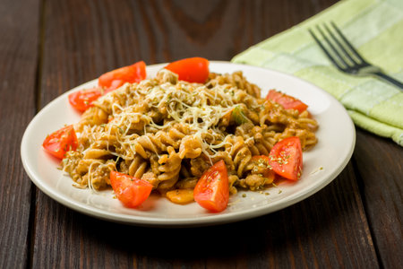 pasta with minced meat, tomato sauce and pieces of tomatoes on a wooden tableの写真素材