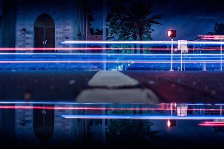 Water reflection of church and over exposure cars speeding by at nightの写真素材