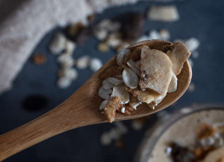 detail of a spoon with muesli with smoothie with banana and oatmeal, muesli and almond milk in a...