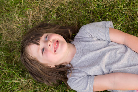 little girl lying on the grass in the park outdoors
