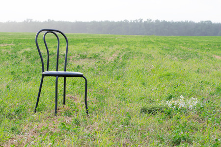 empty chair on the grass in a field near a bouquet of daisiesの写真素材
