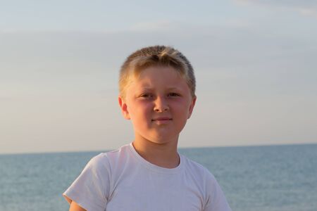 boy in a white t-shirt standing on a sea backgroundの写真素材