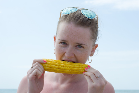 girl eating a boiled corn on the seasideの写真素材