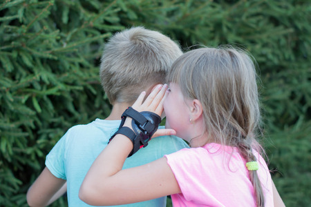 the girl says to the boy's earの写真素材