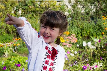 Little girl in Ukrainian embroidery, costs about colors and shows forth his handの写真素材