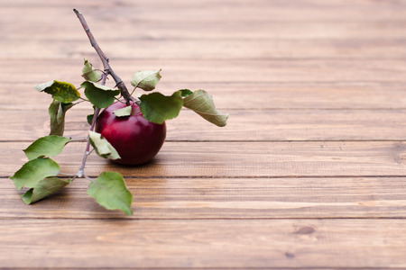 red apple with leaves lying on a wooden table