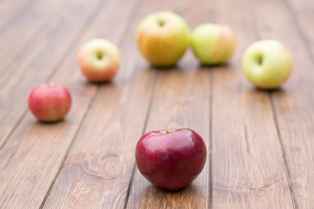 red apple and yellow apples on a wooden table