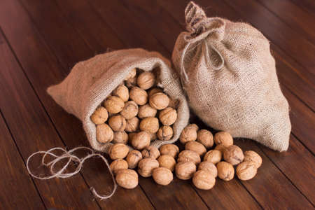 Ripe walnuts in a bag on a wooden table