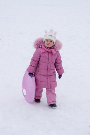 cheerful little girl ride down the hills in winterの写真素材