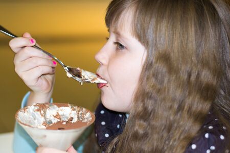 little girl with pleasure eats dessert in cafe close-upの写真素材