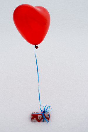 balloon and gift in paper with hearts in the snow on Valentine's Day,の写真素材