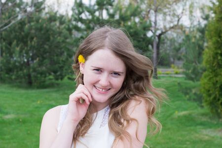 portrait of a smiling young girl with daisies in her hair on the nature backgroundの写真素材