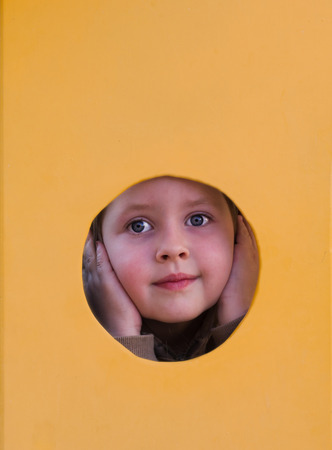 little girl on the playground, his hands on his face looking out the windowの写真素材