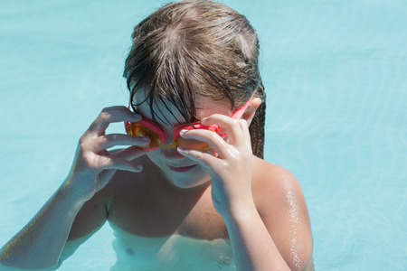 little girl wears glasses at the pool for swimming