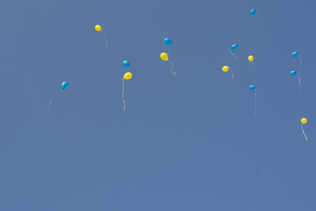 yellow and blue balloons with helium fly to the blue skyの写真素材