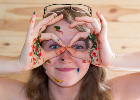 cheerful girl stained with paint on his face grimacesの写真素材