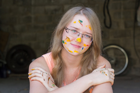 smiling girl with glasses stained painted face sitting in the garage