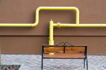 bench near the wall of the house which are connected to the yellow gas pipeの写真素材