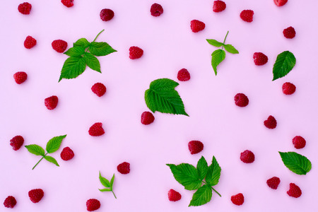 composition of raspberries and raspberry leaves on a pink background close up