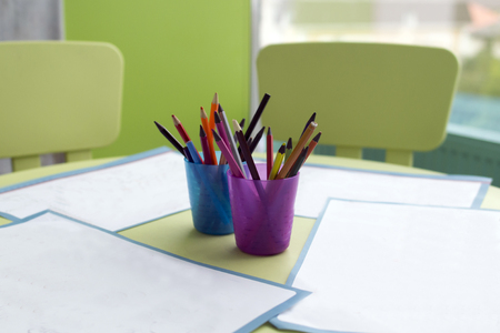 four clean paper blank and colorful pencils on the children's wooden table. close-up