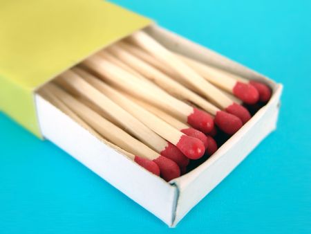 Green box of wooden match sticks on blue background