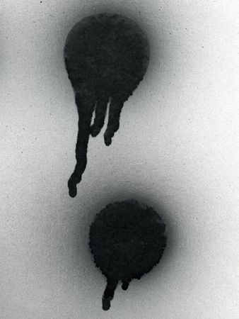two black spray painted spots with drips on white surfaceの写真素材