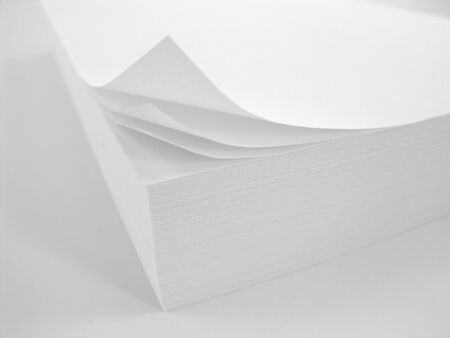 stack of white copy paper with curled corner over white background