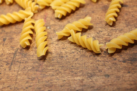 Spiral pasta spilled over old wood backgroundの写真素材
