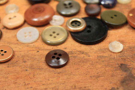 Buttons of various sizes and colors on wood background