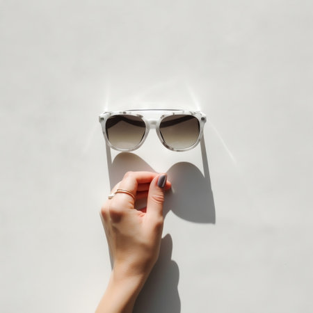 Hand Holding Sunglasses Against White Wall AIの素材