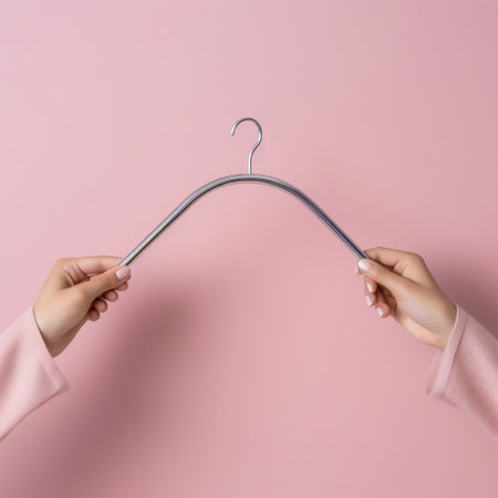Isolated Pink Background with Feminine Hand Holding Empty Hanger Generative AIの素材